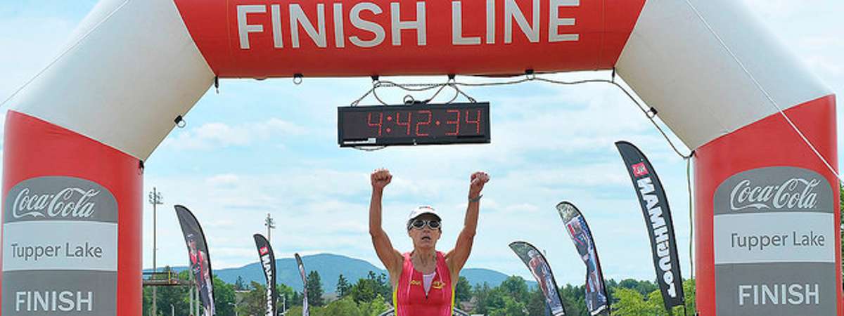 woman holding up arms crossing finish line