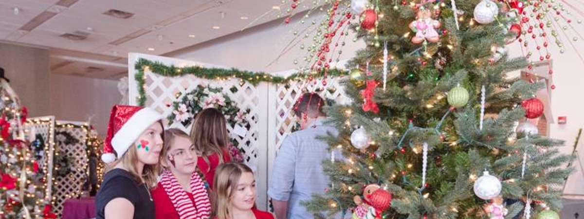 three people looking at decorated holiday tree