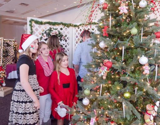 three people looking at decorated holiday tree