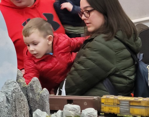 two adults and boy looking at train set
