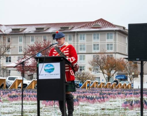 man gives speech at field of flags