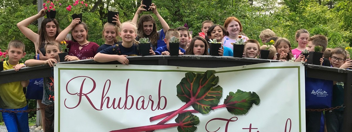 crowd poses behind rhubarb festival sign