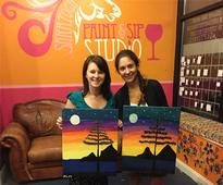 two women holding up paintings