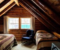 inside a cabin with two beds, chair, window