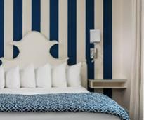 navy blue and white colored hotel room with bed and lamp, striped walls