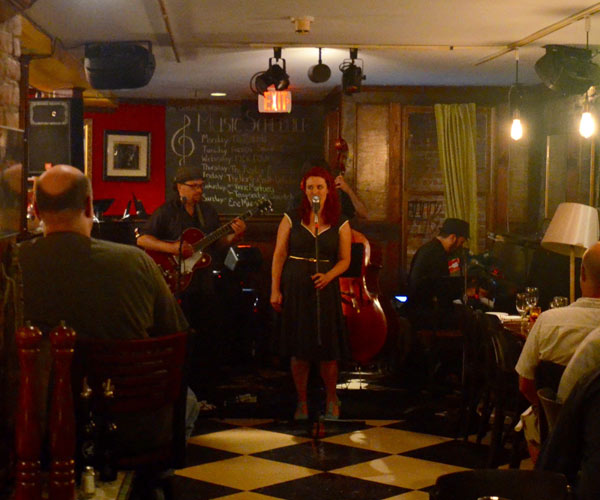 a woman performing at a jazz bar with a band behind her