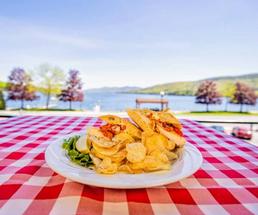 plate of food on table in foreground, lake and trees in background