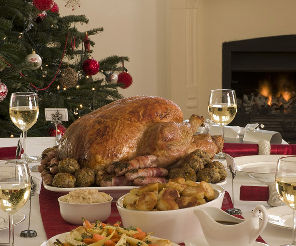 holiday turkey on a table with glasses of wine and other silverware and plates