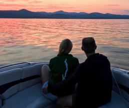 back of couple on a boat watching the sun set
