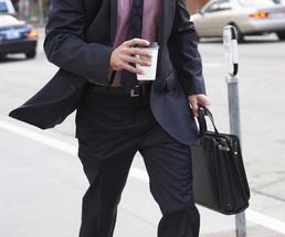 man walking holding coffee and a briefcase
