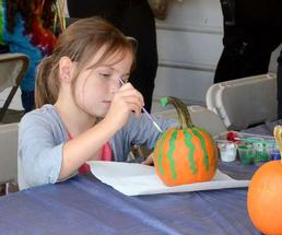 girl painting small pumpkins