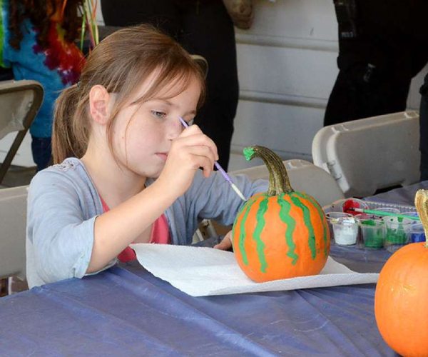 girl painting small pumpkins