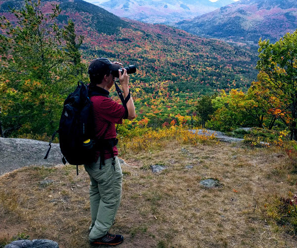 man on mountain in fall taking photos