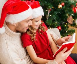 father and daughter reading book on christmas