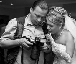 bride and wedding photographer looking at recent photo