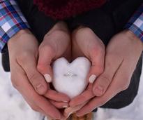 ring in snow heart held in couple's hands