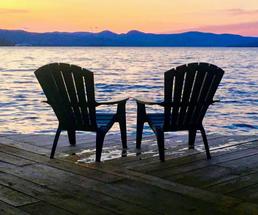 two Adirondack chairs by sunset