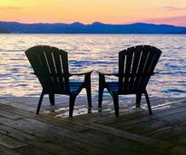 two Adirondack chairs by sunset