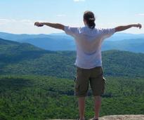 man at summit doing I'm King of the World pose