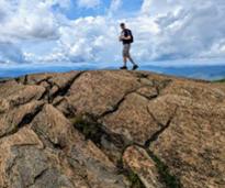 hiker on top of giant summit rock