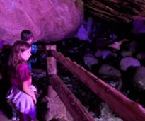 kids inside cave near small waterfall