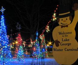 Lake George Winter Carnival snowman sign with lit up trees