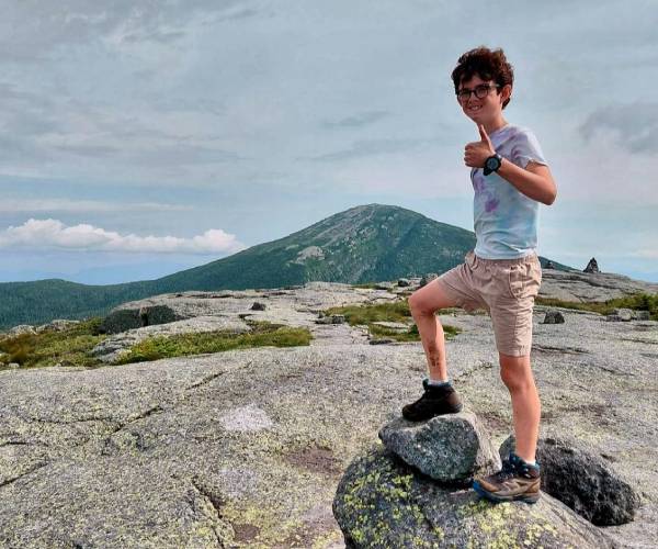 kid on mountain summit giving a thumbs up