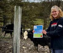 woman with cow plop bingo flier poses by cows