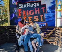 dad and kid pose at photo op at fright fest with fake zombies