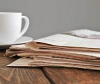 coffee cup next to a pile of newspapers
