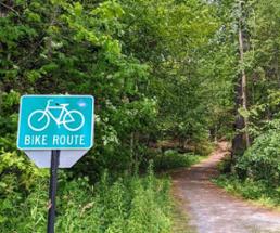 bike route sign by path into woods