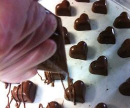 person decorating chocolate heart-shaped truffles
