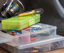 tackle boxes with fishing lures, a fishing reel, and a pair of boots