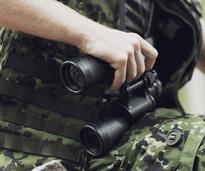 man in camouflage holding a pair of black binoculars