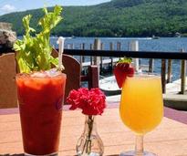 a bloody mary and a mimosa on a table in front of a lake