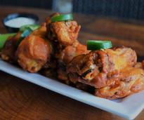 a plate of chicken wings with jalapeno slices