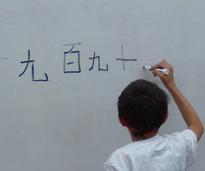 boy writing in a foreign language on a white board