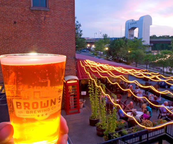hand holding beer looking out over deck by water