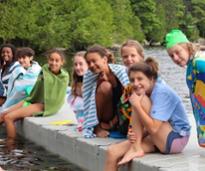 summer camp girls pose on a dock after swimming