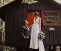 bride and groom pose in front of barn