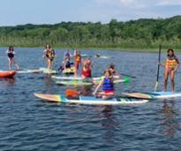 a bunch of people on paddleboards, some doing yoga