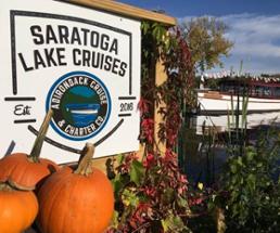 saratoga lake cruises sign with pumpkins by lake with boat