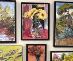 several paintings of flowers hanging in a gallery