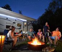 people gathering around a campfire by an rv