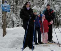 cross-country skiing family poses by signage in woods