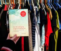 Marie Kondo book held up in front of closet