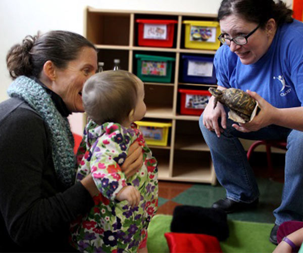 one woman holding a baby and another holding a turtle
