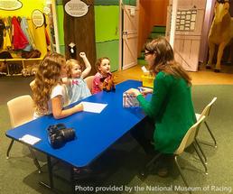 educator teaching three girls at the national museum of racing