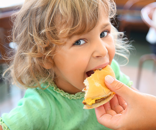 mother's hand feeding daughter a cheeseburger