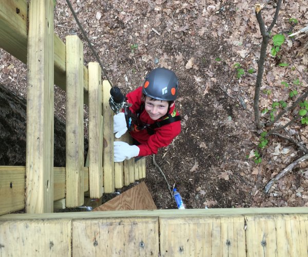 boy climbing a ladder at an aerial adventure course
